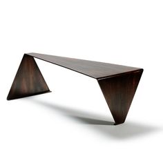 a wooden bench sitting on top of a white floor next to a black object with two triangular shaped legs