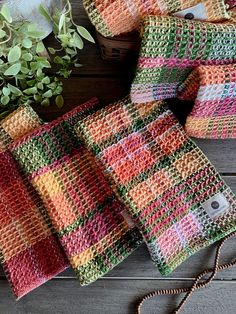 four crocheted squares sitting on top of a wooden table next to a potted plant