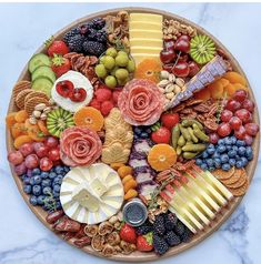 a platter filled with assorted fruits and cheeses on top of a marble counter