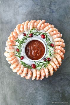 shrimp skewers on a plate with dipping sauce and rosemary sprigs around them