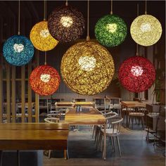 several colorful lights hanging from the ceiling in a room with wooden tables and stools