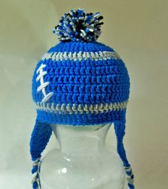 a crocheted blue hat with white and gray letters on it sitting on top of a head mannequin