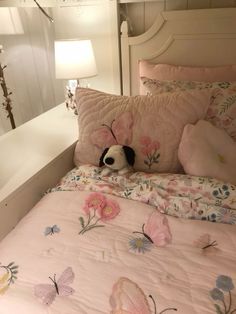 a dog laying on top of a bed with pink sheets and flowers in the comforter