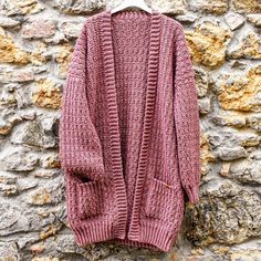 a pink sweater hanging on a stone wall