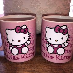 two hello kitty coffee mugs sitting on top of a table