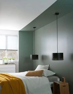 a bed sitting in a bedroom next to a window with two lamps hanging above it