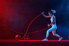 a woman in white tights is holding a red rope while standing on a stage