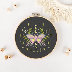 a cross - stitch pattern with a butterfly on it, next to beads and tassels