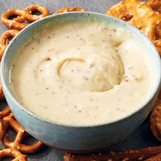 a bowl filled with dip surrounded by pretzels