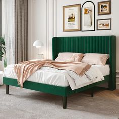 a bedroom with a green headboard and white bedding, framed pictures on the wall