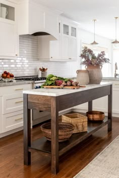 a kitchen with white cabinets and wooden flooring next to an island in the middle