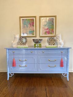 a blue dresser with two vases on top of it and pictures above the drawers