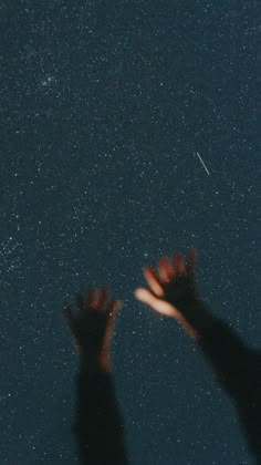 two hands reaching up at the stars in the sky