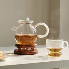 a glass tea pot and cup on a table