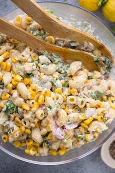 a bowl filled with macaroni salad and two wooden spoons