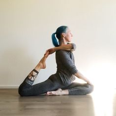 a woman sitting on the floor in a yoga pose with her arms behind her head