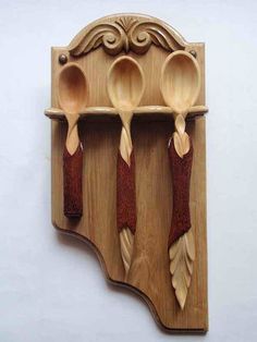 three wooden spoons are mounted to a wall with hooks on the top and bottom