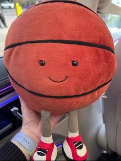 a person holding up a basketball pillow in their hand, with the ball on it's feet