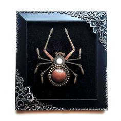 a spider in a black frame with silver filigrees on it's back