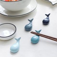 small blue whale figurines sitting next to chopsticks on a white table