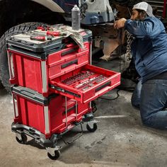 a man working on a red toolbox in front of a truck with tools inside