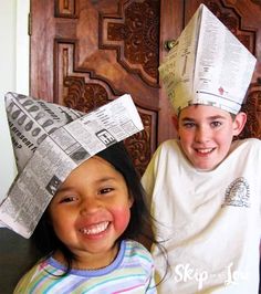 two children wearing paper hats on their heads and one child is smiling at the camera