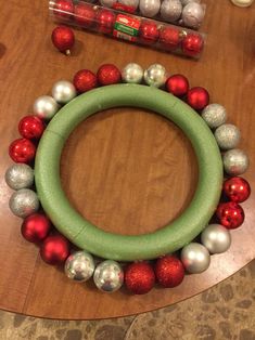 a christmas wreath made out of ornaments on top of a wooden table next to some candy