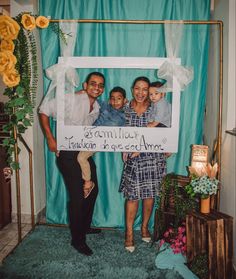 a man and two women holding a sign in front of a blue backdrop with flowers