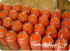 many jars filled with red sauce sitting on top of a table