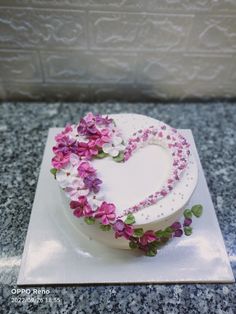 a heart shaped cake decorated with flowers on a counter top in the shape of a heart