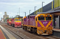 three trains are parked on the train tracks next to each other in front of a building