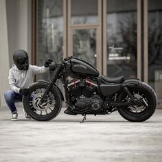 a man kneeling down next to a motorcycle on the ground in front of a building