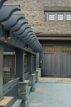 the front entrance to a large house with stone steps and benches under an awning