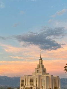 a large white building with a steeple and trees in front of it at sunset