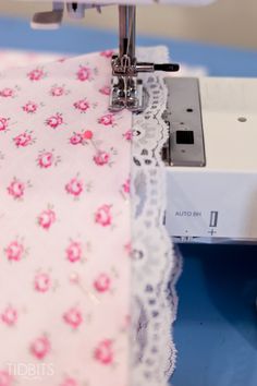 the sewing machine is next to the pink flowered tablecloth