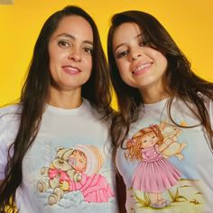 two young women standing next to each other in front of a yellow wall wearing matching tshirts