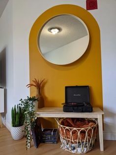 there is a mirror on the wall above a table with a laptop and potted plants