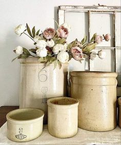 some white flowers are in vases on a table next to an old window frame