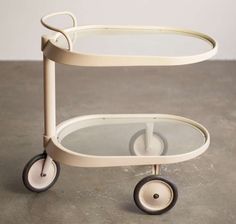 a white plastic cart with two wheels and a glass top on the bottom, sitting on a concrete floor