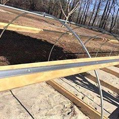 a wooden structure with metal bars on it in the middle of some dirt and trees