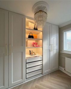 an empty room with white cupboards and shelves filled with purses, shoes and bags