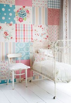 a white chair sitting next to a baby crib in front of a colorful wall