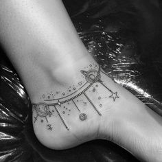 a woman's foot with a tattoo on it and stars in the sky above