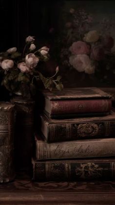 a vase with flowers sitting on top of three books next to each other in front of a painting