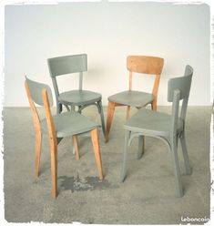 three wooden chairs sitting next to each other in a room with cement flooring and white walls