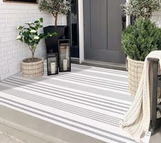 two planters are sitting on the front porch next to a door and potted plants