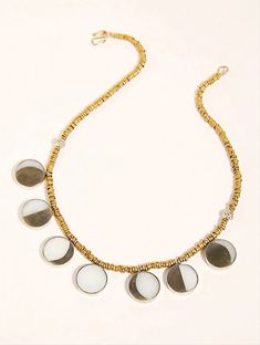 a gold and white necklace with five circles on the front, hanging from a golden chain