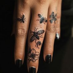 a woman's hand with tattoos on her fingers and two bees sitting on top of each other