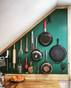 a green pegboard with pots and pans hanging on it's wall next to an orange