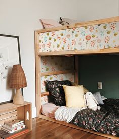 there is a bunk bed in the room with flowers on the wall and pillows on the floor